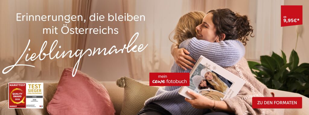 Zwei Personen umarmen sich liebevoll und halten ein CEWE FOTOBUCH in den Händen.