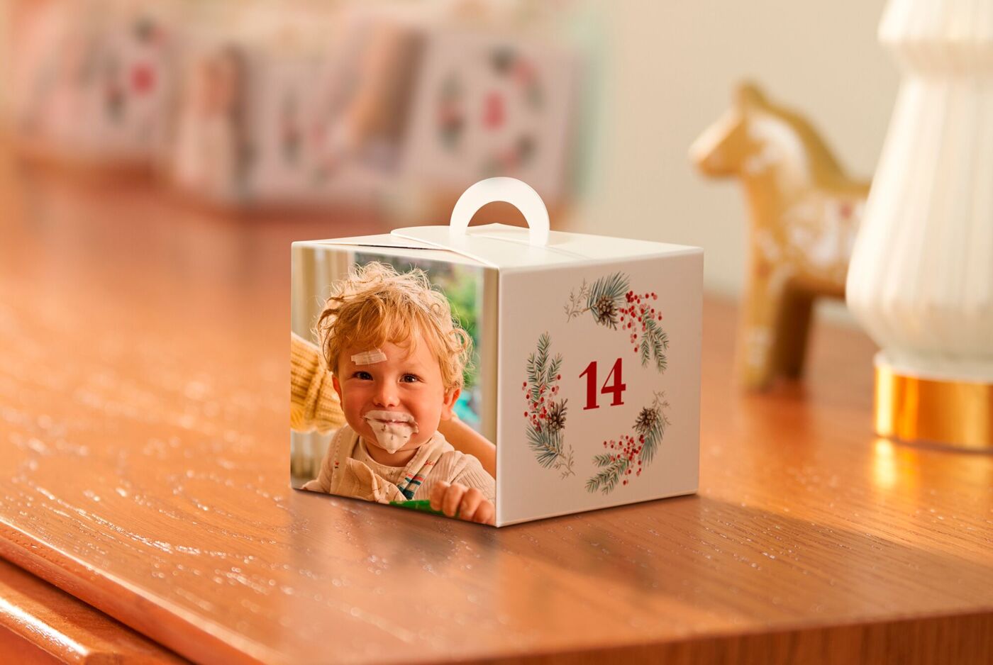 CEWE Schachtel Adventskalender mit gestalteter Geschenkbox auf Holzkommode. Lichter und Dekoration