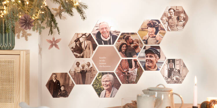 An einer Wand hinter einem Esstisch mit Tee und Keksen hängen zwölf hexxas-Wandbilder. Die sechseckigen Kacheln bilden einen Familienstammbaum aus Fotos. Auf einer Kachel in der Mitte stehen die Worte „Familie ist die Heimat des Herzens“.